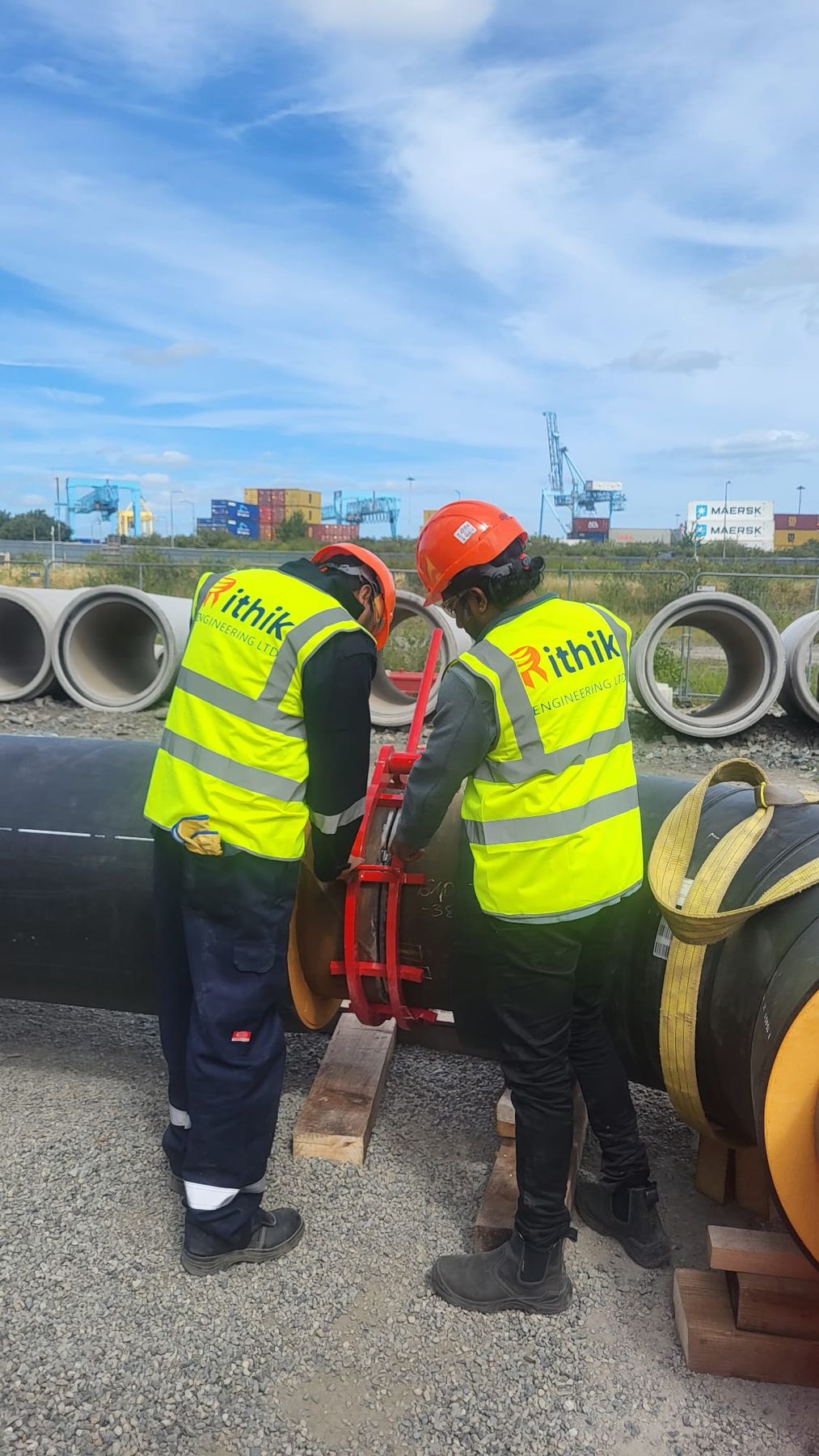 Two Rithik crew members working on a large pipe