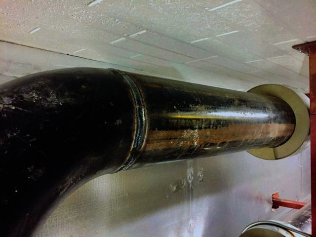 Welded pipe bend passing through a wall sleeve