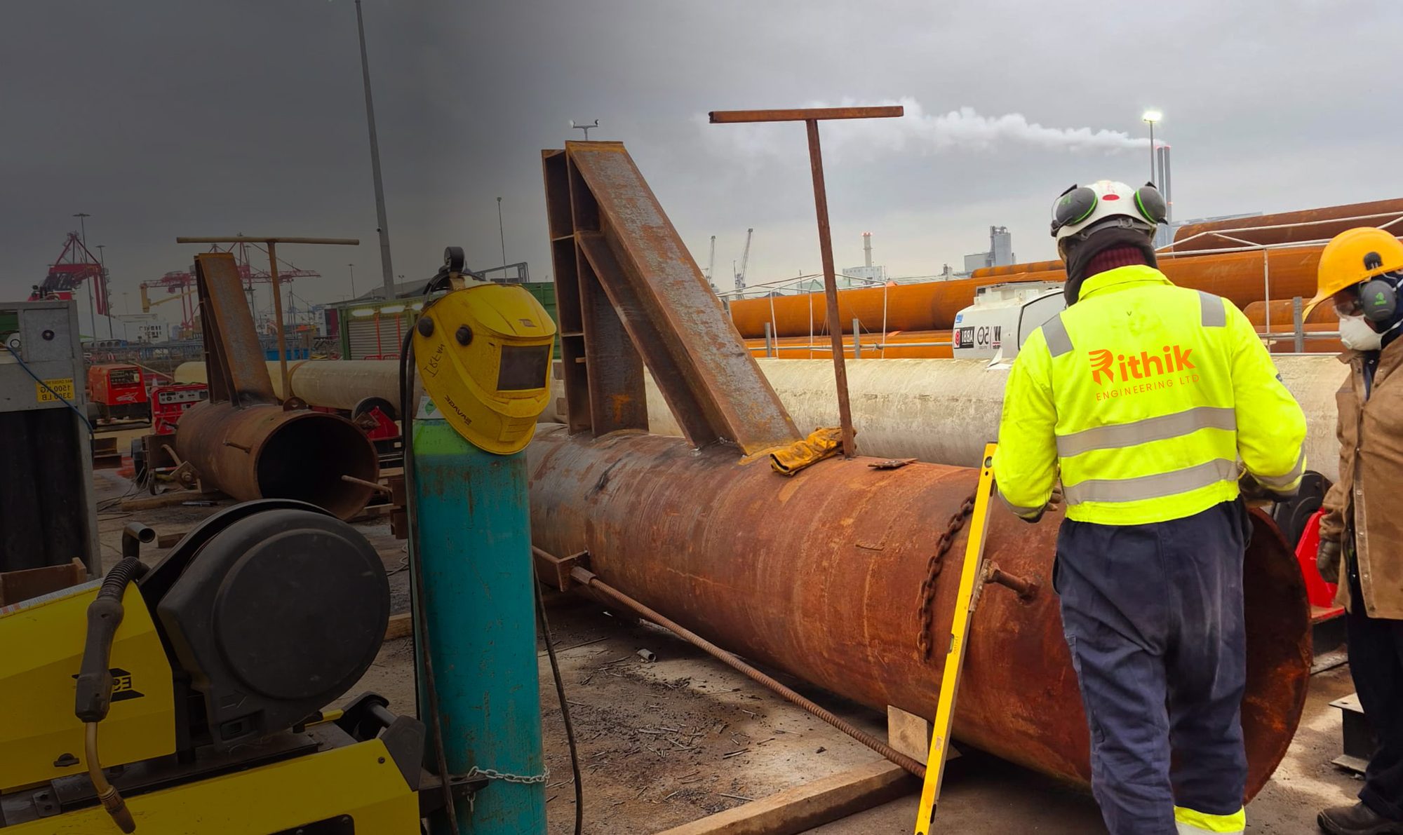 Rithik crew member in a hi-vis jacket beside a large steel pipe on site